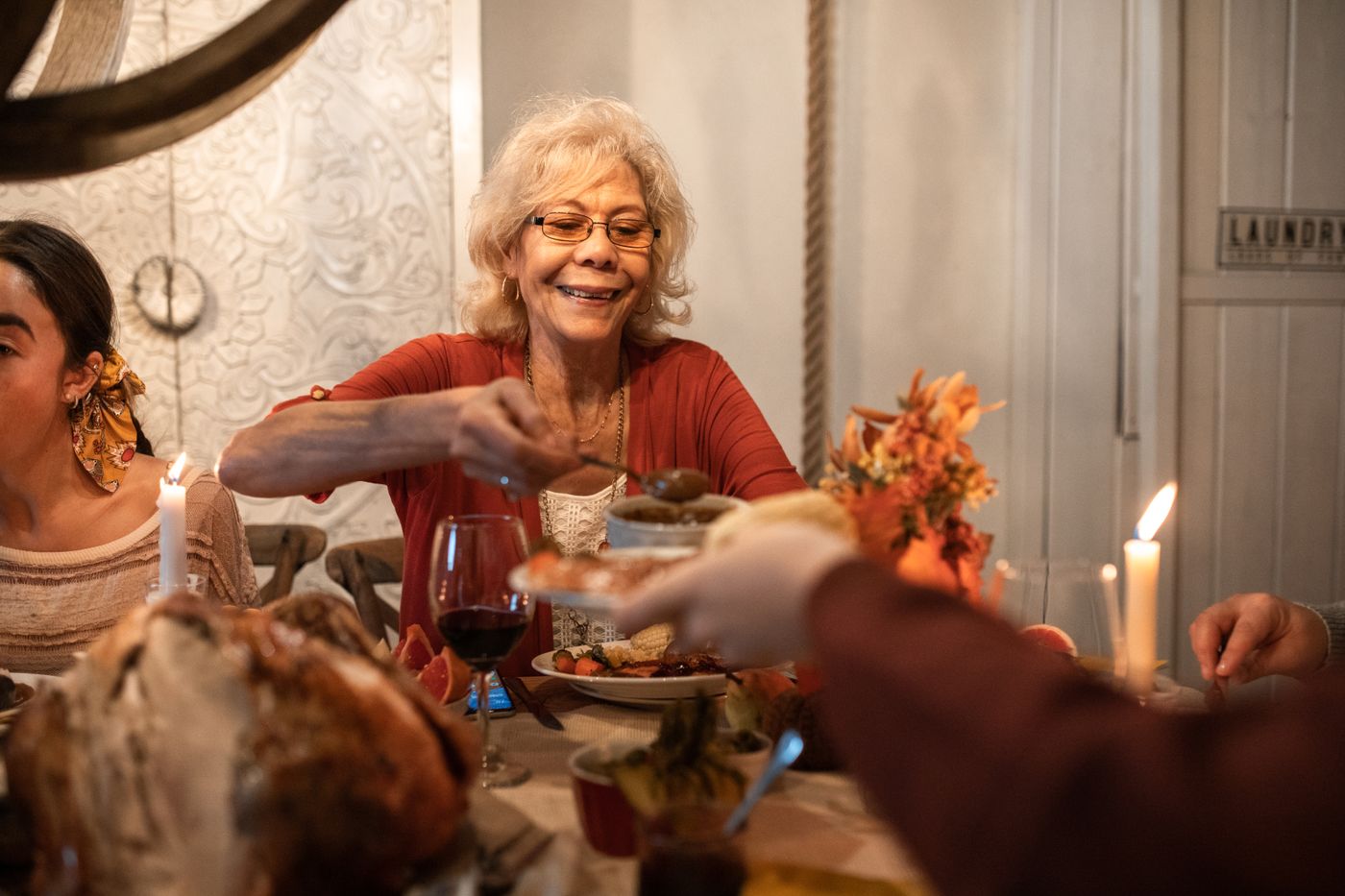 A resident smiling as she serves herself at a warm, candlelit dinner table